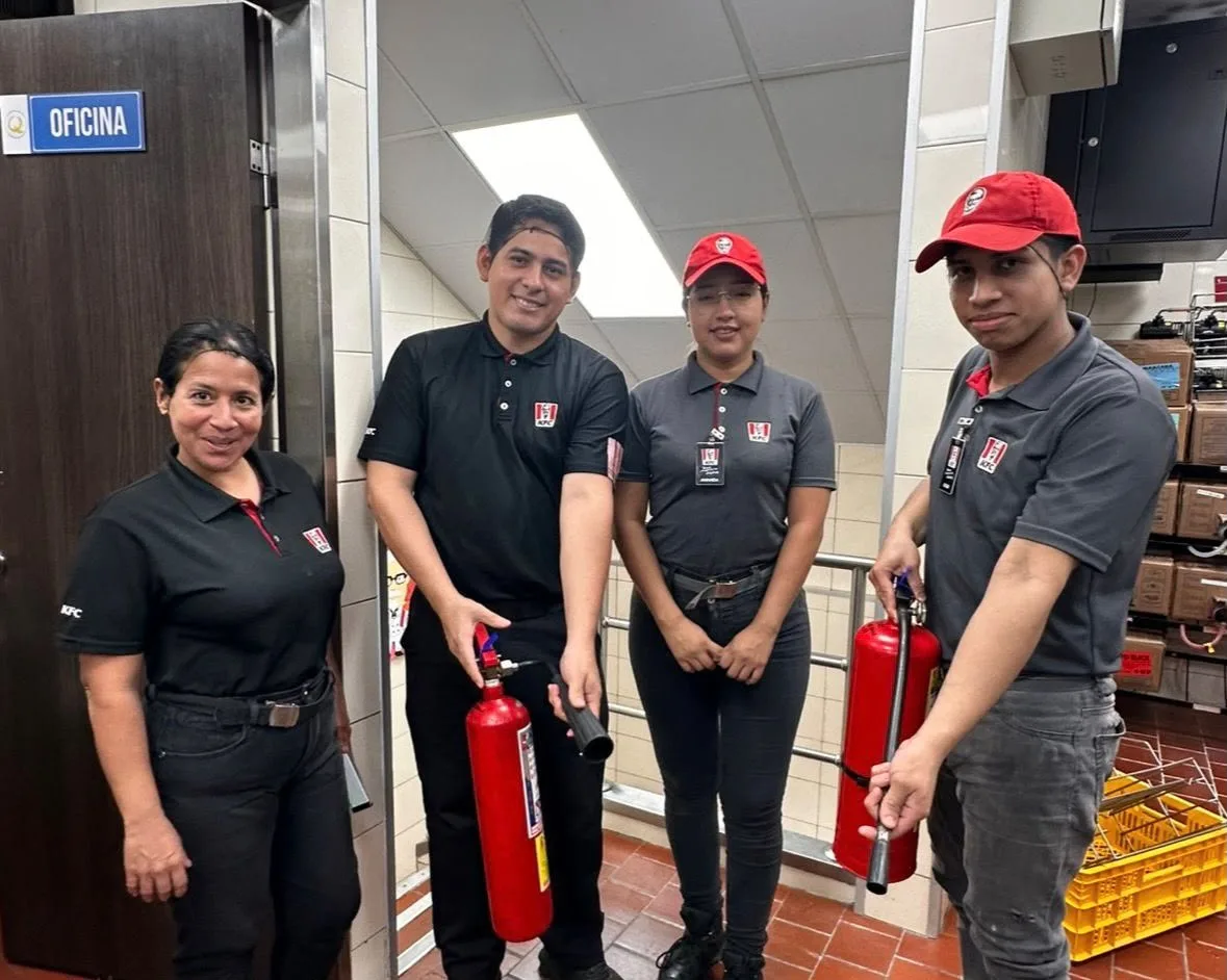 Personal KFC posando con extintores en cocina